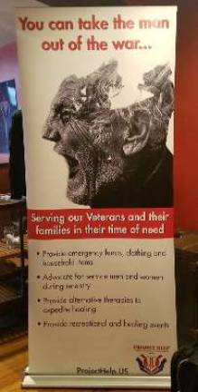 A large poster for local veterans' support organization Project Help stands in the foyer of the Stanhope House