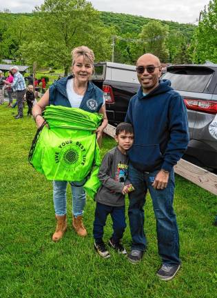 Councilwoman Christine Quinn, holding backpacks, poses with Roderick Rodriguez and his son Reyan.