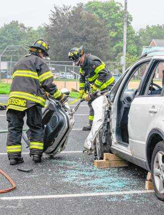 Firefighters pull the driver’s door off a car.