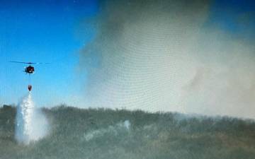 An aerial tanker drops water on a wildfire in West Milford as smoke billows into the air. (Photo courtesy of Curtis J. Dorph)