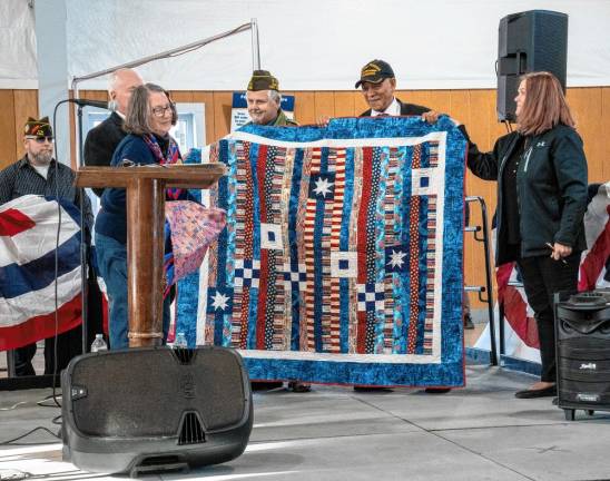 <b>Carol Johnson presents a Quilt of Valor to keynote speaker Emerson Crooks, second from right, and Frank Toth, center, who received a certificate of appreciation.</b>