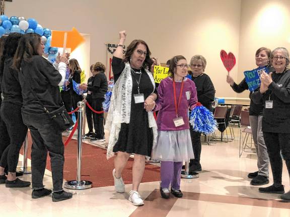 <b>Volunteers welcome a guest and her buddy walking the red carpet into the prom.</b>