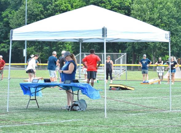 Team members report their scores at tables on the field.