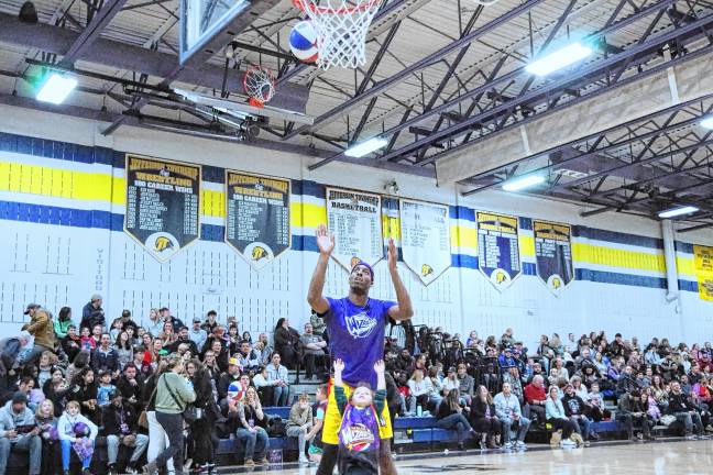 HW2 Kayden Toth, 3, of Jefferson gets help taking a shot from Harlem Wizards basketball player Kamil ‘Dragon’ Brown. Kayden’s uncle Robby, who teaches math at the middle school, was playing for the Jefferson team. (Photos by George Leroy Hunter)