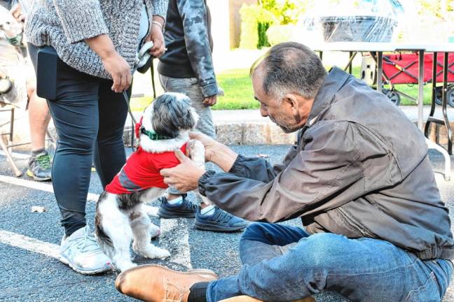 The Rev. Dr. Jack DiMatteo blesses a dog named Toby in the church parking lot. (Photo by Maria Kovic)