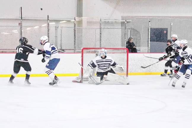 Chatham and KJS United hockey players focus on the puck as it soars high above them.