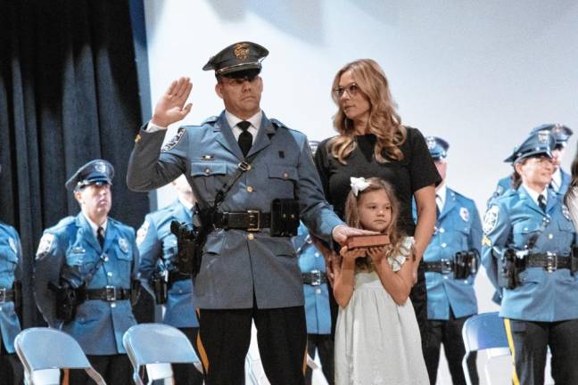 Capt. Thomas Snyder takes the oath for his promotion as his daughter holds the Bible.