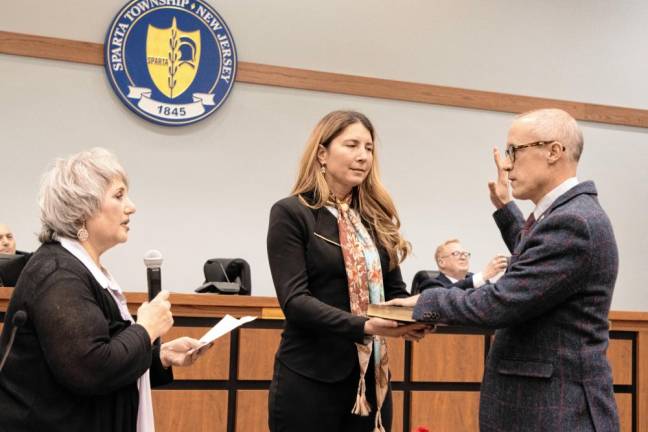 NC Neill Clark takes the oath of office as mayor for 2025. His wife, Alexandra Miller Clark, holds the Bible and Township Clerk Roxanne Landy administers the oath.