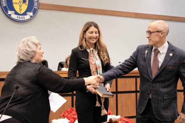 Township Clerk Roxanne Landy congratulates Mayor Neill Clark after he takes the oath of office as mayor for the second year in a row. His wife, Alexandra Miller Clark, is center.