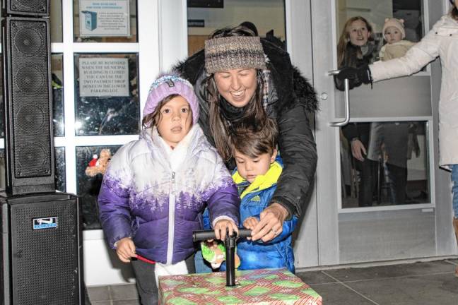 The Gentile family, winner of the 2023 home decorating contest, push a control to light the Christmas tree.