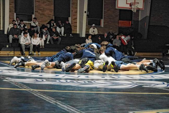 Pope John XXIII Regional High School wrestlers gather at the center of the mat before the start of the match with Sparta High School on Jan. 9.