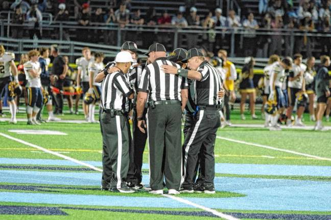 <b>Officials in a huddle at the center of the field before the game begins.</b>