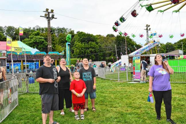 Carnival visitors look up at a ride.