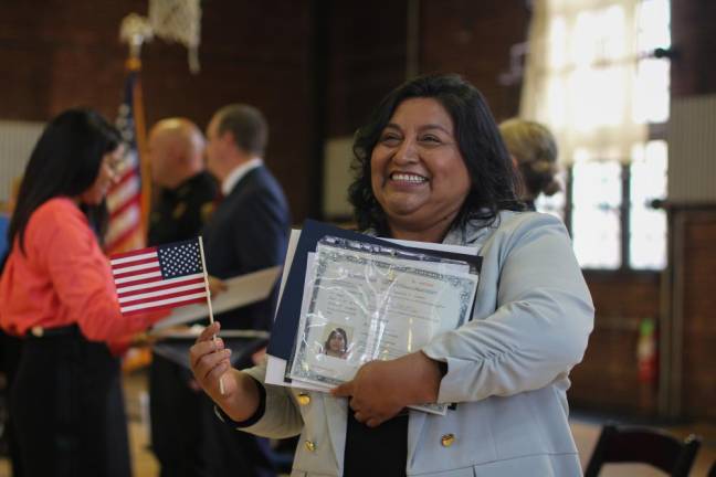 A new citizen smiles for a photo with her documents at a naturalization ceremony in Newburgh. Photo: Brianna Kimmel