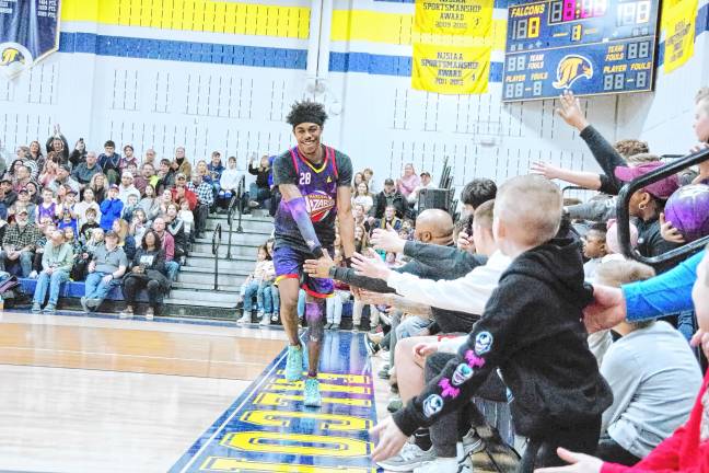 HW6 A Harlem Wizards basketball player trots around the perimeter of the court while greeting the fans.