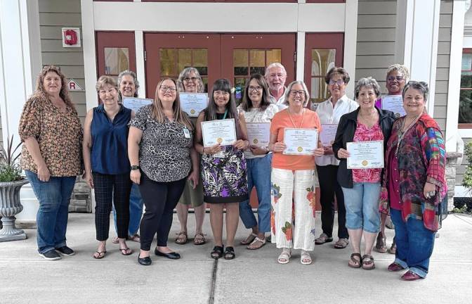 <b>Recent graduates of the International Doula Life Movement (IDLM) certification program hold certificates at a recent graduation ceremony at the Karen Ann Quinlan Home for Hospice in Fredon. From left are Lisa O’Hara, president of Friends of Karen Ann Quinlan Hospice; Mary Ellen Quinlan, chairwoman of the Karen Ann Quinlan Memorial Foundation; Barbara Steen, an end-of-life doula (EOLD); Anna Adams, founder of IDLM; EOLDs Dawn Harris, Debra Walck, Carol Cummins, Brian Cummins, Kim Germain, Dawn Bump, Barbara Palumbo and Lee Ellison; and Pamela Carter, executive director of IDLM. (Photo provided)</b>