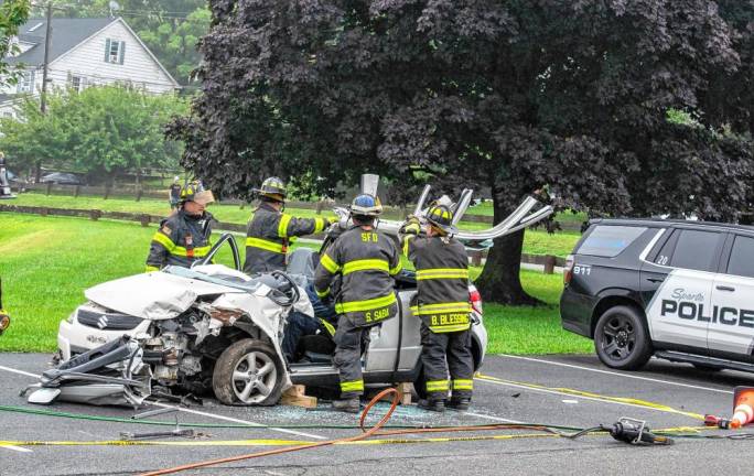 Firefighters remove the roof of a car,