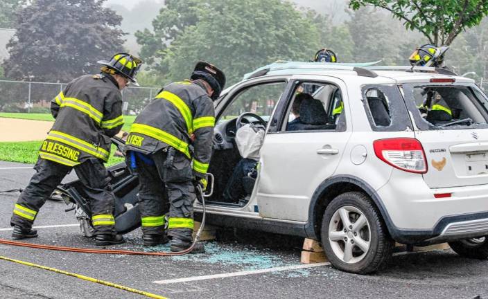 Firefighters pull the driver’s door off a car.