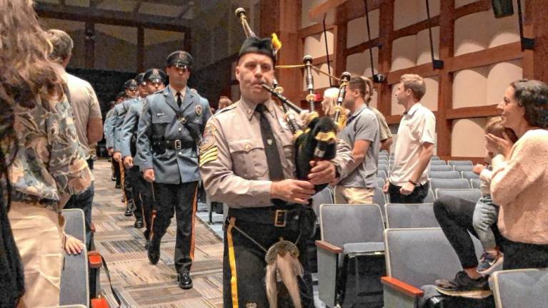 Sparta police officers follow a bagpiper into the ceremony in the Sparta High School auditorium Aug. 30. (Photo by Kathy Shwiff)