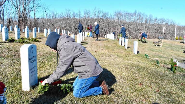 A volunteer places a wreath on a grave Saturday, Dec. 14 at the Northern New Jersey Veterans Memorial Cemetery in Sparta. (Photo by Maria Kovic)